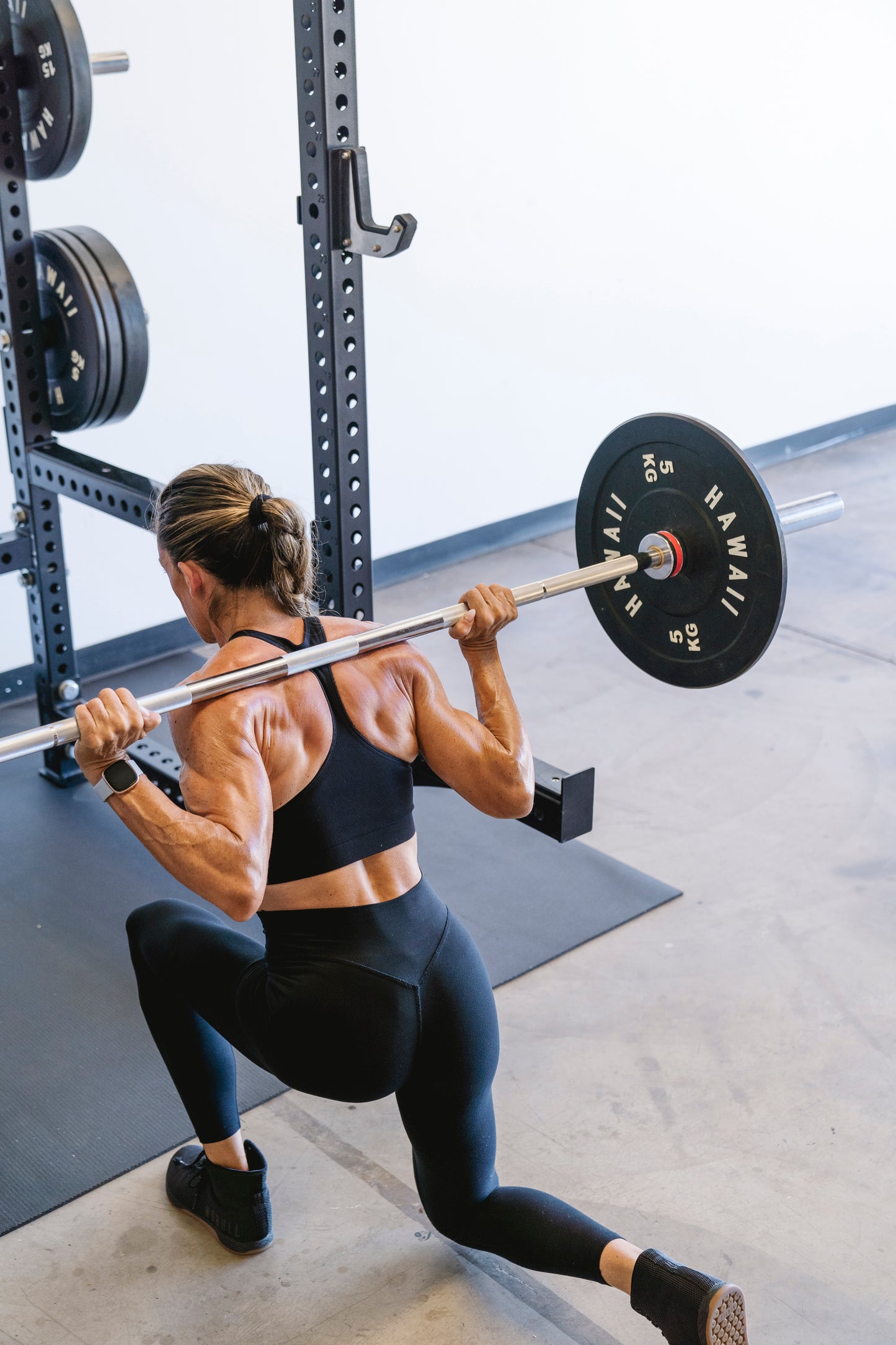 Athlete squatting in the Hawaii power cage with bumper plates